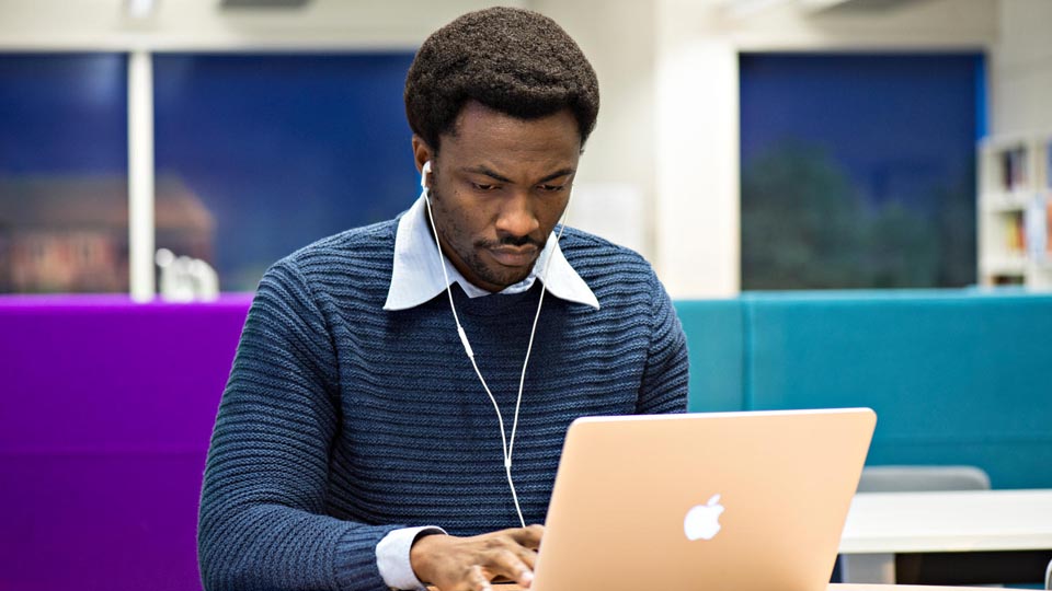 a student sitting at a desk using a laptop